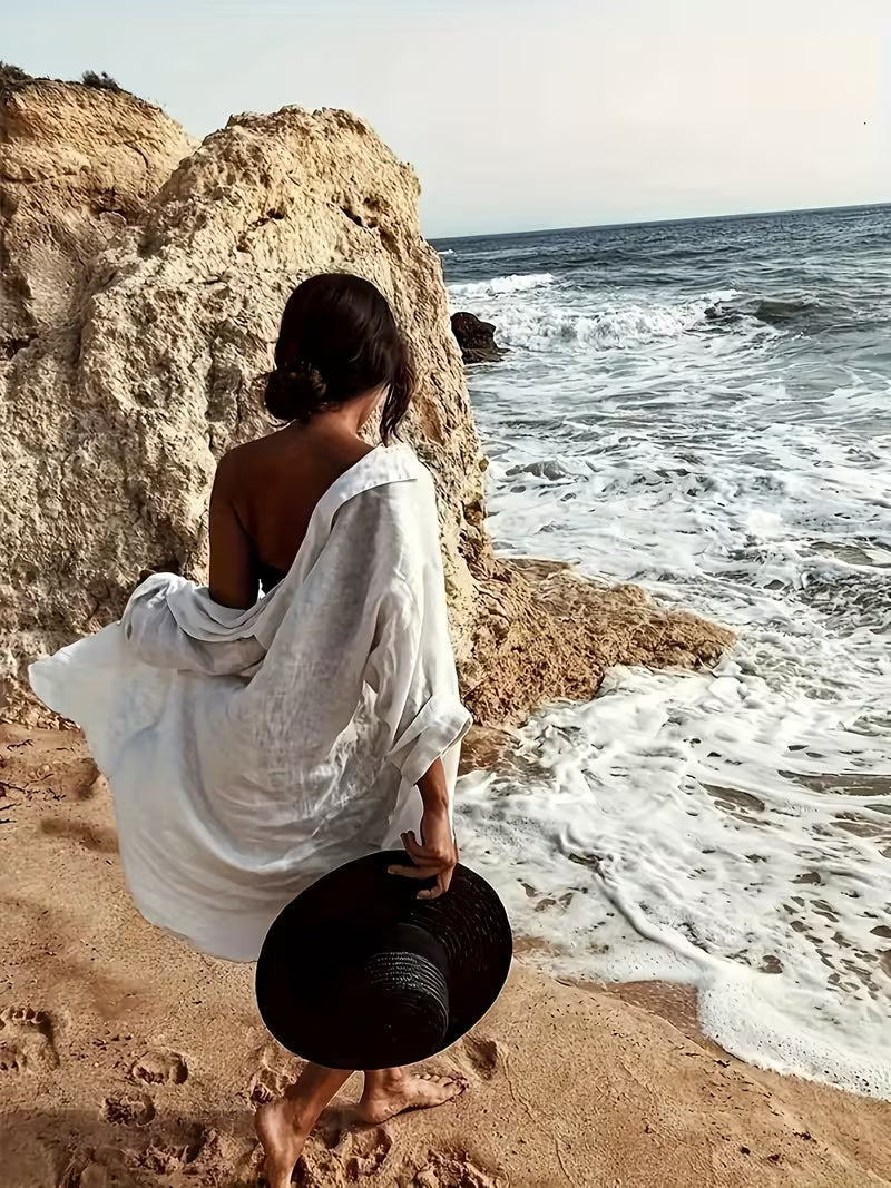 La chemise de bain blanche qui fait toute la différence dans votre dressing d’été. Subtilement semi-transparente, elle joue avec la lumière pour révéler juste ce qu’il faut, créant un équilibre parfait entre élégance et sensualité