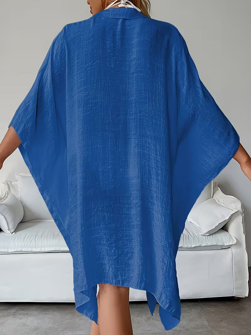 Chemise de plage loose, féminine et subtilement sensuelle, à la coupe fluide qui effleure la silhouette pour un look chic, léger et irrésistiblement estival