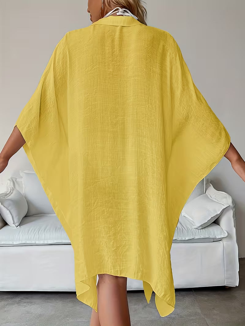 Chemise de plage loose, féminine et subtilement sensuelle, à la coupe fluide qui effleure la silhouette pour un look chic, léger et irrésistiblement estival
