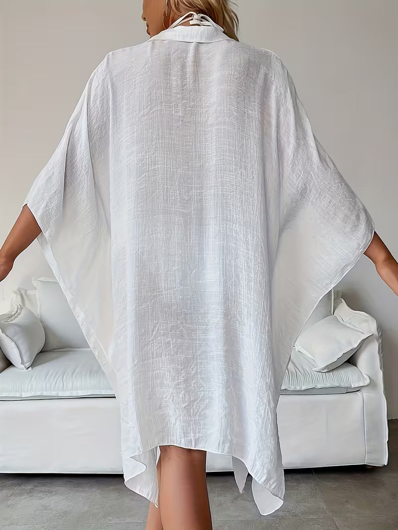Chemise de plage loose, féminine et subtilement sensuelle, à la coupe fluide qui effleure la silhouette pour un look chic, léger et irrésistiblement estival